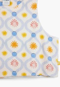 Biely textil s opakujúcim sa vzorom modrých kruhov, žltých a oranžových slnečných výbuchov a vlnitých sivých čiar, s jemnou textúrou.