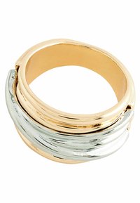 Ring i guld och silver staplad med släta, blanka ytor med böljande mönster och rund form, som framhäver kontrasterande metalliska färger.