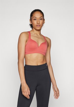 Koral sports-bh med scoop-hals, brede stropper og glatt tekstur. Båret med svarte høyhente leggings, som viser en fit silhuett.