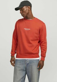 Rode sweatshirt gemaakt van zachte stof, met een ronde hals en ribgebreide mouwen. Tekstlogo "Originals Studio" in het wit gedrukt op de borst.