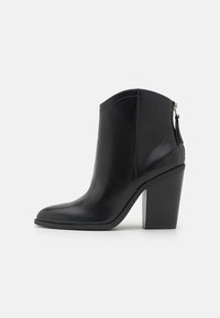 Schwarze Lederanzugstiefel mit spitzem Absatz, hohem Blockabsatz und einem Reißverschluss auf der Rückseite. Glatte Textur mit minimalen Nähdetails.