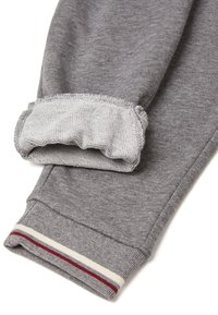 Rukáv šedé mikiny s žebrovaným manžetem, který má červené a bílé pruhy. Vnitřní manžet je elastický s texturovanou šedou tkaninou.