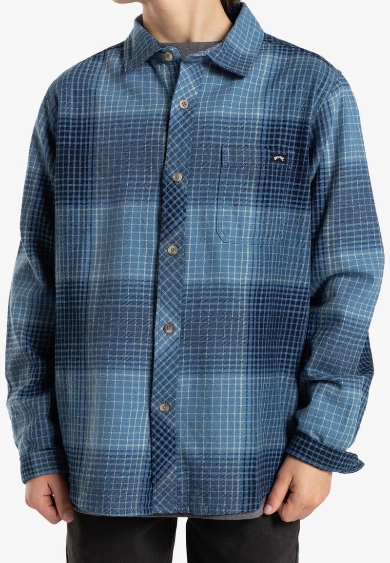 Niebieska koszula flanelowa w kratę z zapięciem na guziki z przodu, kieszenią na piersi oraz kontrastowymi ciemnoniebieskimi i jasnoniebieskimi wzorami w kratę.
