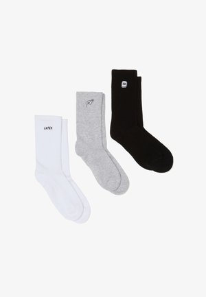Trois paires de chaussettes : blanches avec le texte "LATER", grises avec un motif de stylo, et noires avec le logo "ESC". Texture côtelée et différentes couleurs.