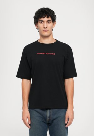 Black cotton t-shirt with a round neckline and short sleeves, featuring red text "HUNTING FOR LOVE" centered on the chest.