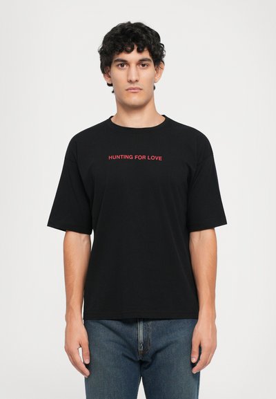 Czarny bawełniany t-shirt o luźnym kroju, z krótkimi rękawami i napisem "HUNTING FOR LOVE" na czerwono na wysokości klatki piersiowej.