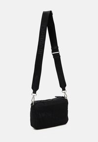 Schwarze Schultertasche mit einem strukturierten, gesteppten Design. Verfügt über einen Reißverschluss und einen verstellbaren Riemen mit Logo. Hergestellt aus weichem Stoff.