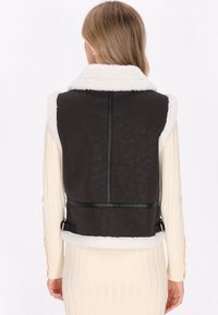 Zwarte nepleer vest met een witte schapenvacht kraag, met een slim fit en details op de achterkant. Versterkt met verstelbare zijbanden.