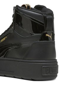 Baskets montantes noires Puma avec semelle épaisse, accents noirs brillants, logos Puma dorés sur les côtés et le talon, et col rembourré autour de la cheville.