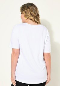 Bílý tričko s krátkým rukávem a kulatým výstřihem, s jemnou texturou a volným střihem, viditelné švy na švech.
