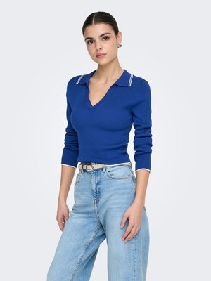 Blue ribbed knit pullover with a V-neck and white-striped collar, paired with light blue wide-leg jeans, featuring a silver belt.