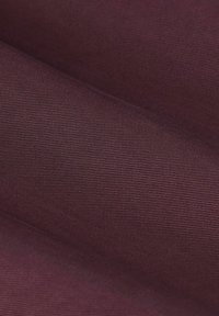 Bordeauxkleurige gestructureerde stof met een geribbeld patroon, met zachte contouren en een lichte glans, geschikt voor diverse textieltoepassingen.