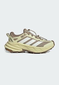 Beige and brown Adidas Terrex trail running shoe with white stripes, Gore-Tex upper, and rugged Continental rubber sole, side view.