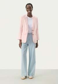 Svetloružový ľanový blazer s dvoma gombíkmi, skombinovaný s voľnými svetlomodrými denimovými nohavicami a bielymi teniskami. Pod ním je obyčajné biele tričko.