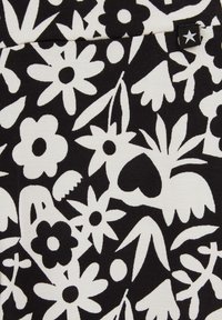 Fekete szövet, amelyen monokróm virágminták találhatók, különböző stilizált virágokkal és levelekkel, fehér színben, változó formákkal és méretekkel.