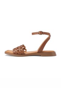 Sandal in pelle marrone con un design floreale a taglio sulla cinturini anteriore, soletta piatta, cinturino alla caviglia regolabile e superficie liscia.