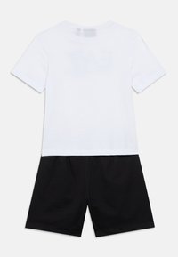 Valge puuvillane T-särk lühikeste varrukatega ja ümar kaelus, kombineeritud mustade puuvillaste lühikestega, millel on elastne vöökoht.