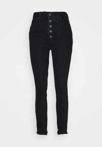 High-waisted black denim jeans with a button fly, five pockets, skinny fit, and frayed hem detail at the ankle.