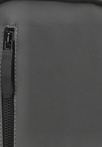 Funda de tela negra con cremallera, con una superficie texturizada, que presenta una cremallera detallada y costura a lo largo de la costura.