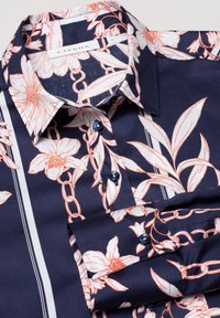 Mörkblå skjorta med blommönster och kedjemönster i korall, med krage, knapplåsning och slät tygtextur.