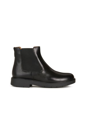 Botín Chelsea de cuero negro con paneles laterales elásticos, punta redonda y suela de goma texturizada con un ligero tacón.
