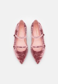 Różowe baletki z aksamitnego materiału, z ostrymi noskami, wyposażone w dwie cienkie ramiączka z okrągłymi ozdobami oraz gładką różową wkładką.
