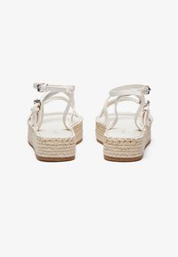 Witte espadrille sandalen met gevlochten jute platformzolen, voorzien van dunne banden en verstelbare enkelgespen, met een minimalistisch ontwerp.