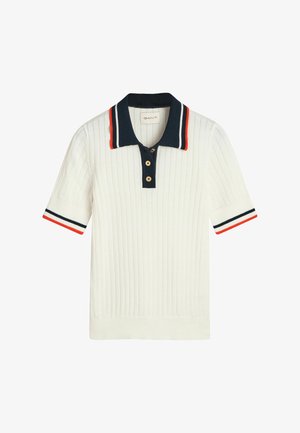 Camisa polo blanca con estilo acanalado y cuello azul marino, que presenta acentos a rayas rojas y azules marino en las mangas y una tapeta de tres botones. Material de mezcla de algodón.