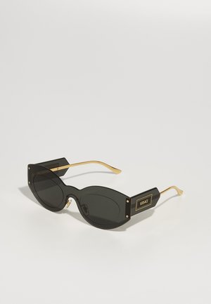Gafas de sol negras de gran tamaño con lentes ovalados, acentos metálicos dorados en las varillas y puntas cuadradas audaces. Presenta la marca en el lateral.