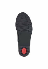 Semelle de chaussure en caoutchouc noir avec un motif de sculpture texturé et un accent rouge au centre. Design plat avec un bout arrondi.