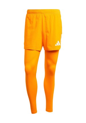 Oranje sportshorts met een elastische tailleband en een witte logo aan de zijkant, gecombineerd met bijpassende oranje compressieleggings. Soepele textuur.