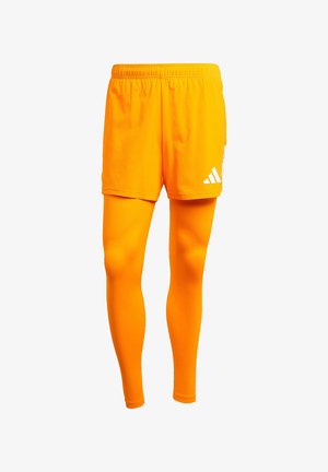Oranje sportshorts met een elastische tailleband en een witte logo aan de zijkant, gecombineerd met bijpassende oranje compressieleggings. Soepele textuur.