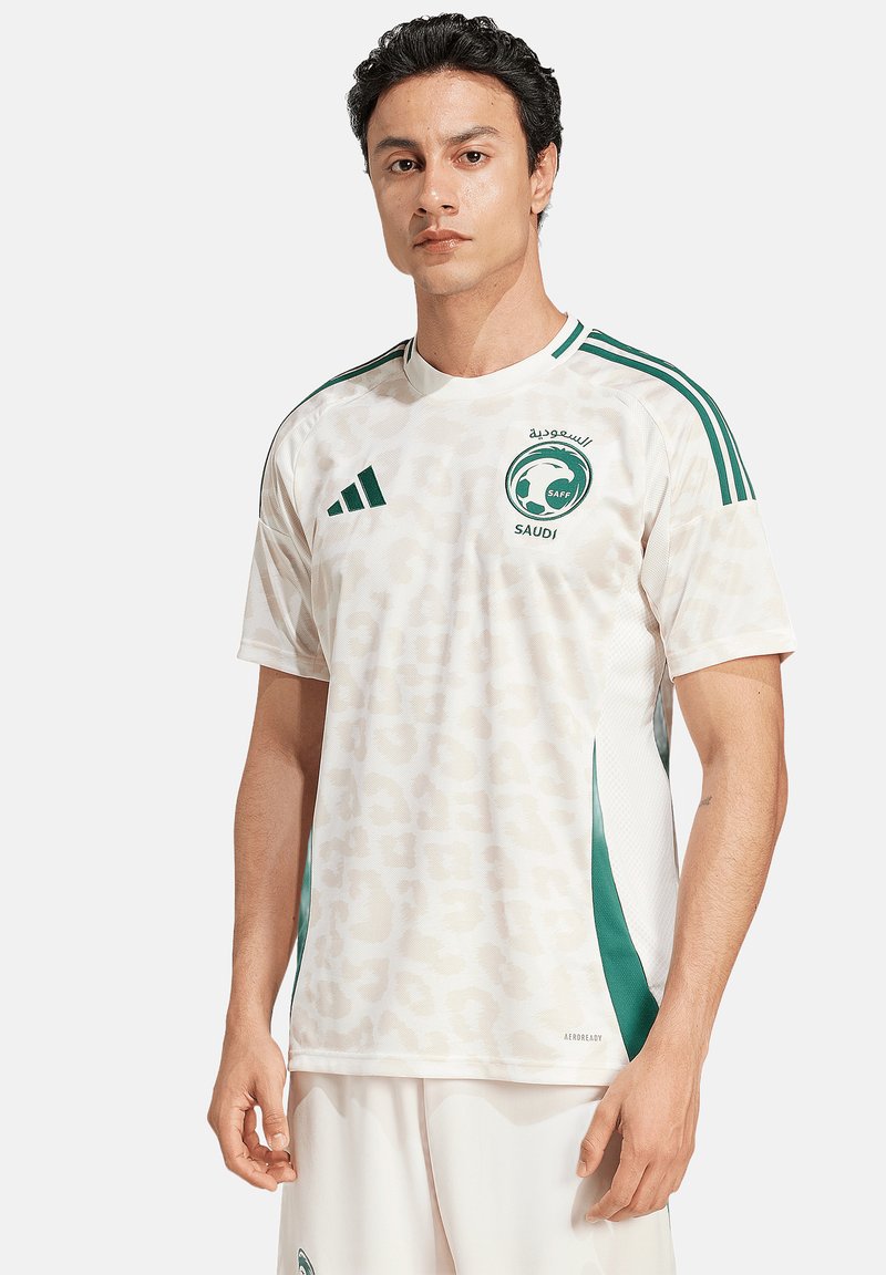 Maglia sportiva bianca con una sottile stampa leopardata, dettagli verdi e righe. Presenta un collo rotondo e il logo "Saudi" sul petto.