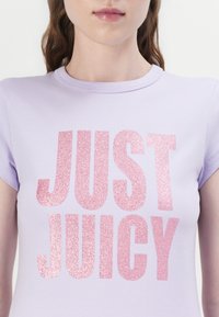 Saldžiai violetinė trumpomis rankovėmis marškinėliai su didelėmis rožinėmis blizgiomis raidėmis "TIK TIKRAI SODRUS" priekyje. Lygi audinio tekstūra su klasikinio apvalaus kaklo dizainu.