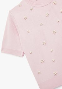 Rosa kurzärmliges Strickoberteil mit rundem Halsausschnitt, das mit perligen Verzierungen auf dem Stoff geschmückt ist. Glatte Textur und taillierte Passform.