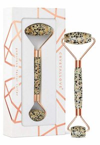 Jadeitowa rolka do twarzy w plamkowanym beżu i czerni z różowo-złotą metalową ramą, zapakowana w białe pudełko z geometrycznymi akcentami.