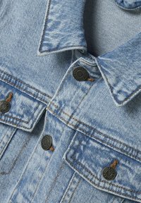 Hellblaue Jeansjacke mit spitzem Kragen, Metallknöpfen und Brusttaschen. Die Nähte sind in kontrastierendem Orange gehalten.