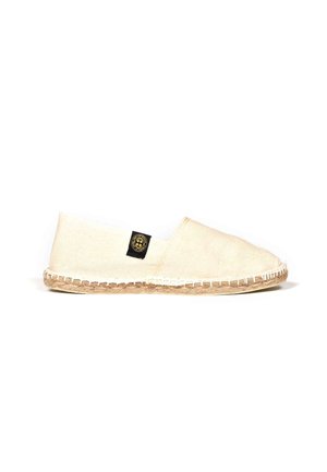 Espadrille en toile beige avec une semelle en jute, ornée d'une étiquette noire et de coutures le long des bords. Design simple et slip-on.