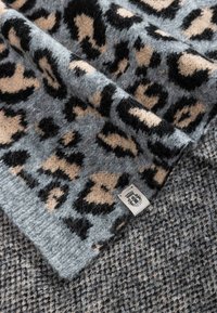 Wool blend blanket featuring a grey leopard print design on one side and a textured houndstooth pattern in darker grey on the reverse.