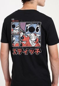 Černé tričko s barevnými kreslenými grafikami na zadní straně, zobrazujícími různé výrazy, s textem v japonštině a čísly nad designem.