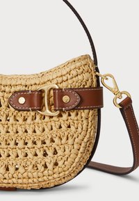 Austiņas no salmu auduma viegli bežā ar brūnām ādas akcentiem, ar zeltainu sprādzi un regulējamu jostu.