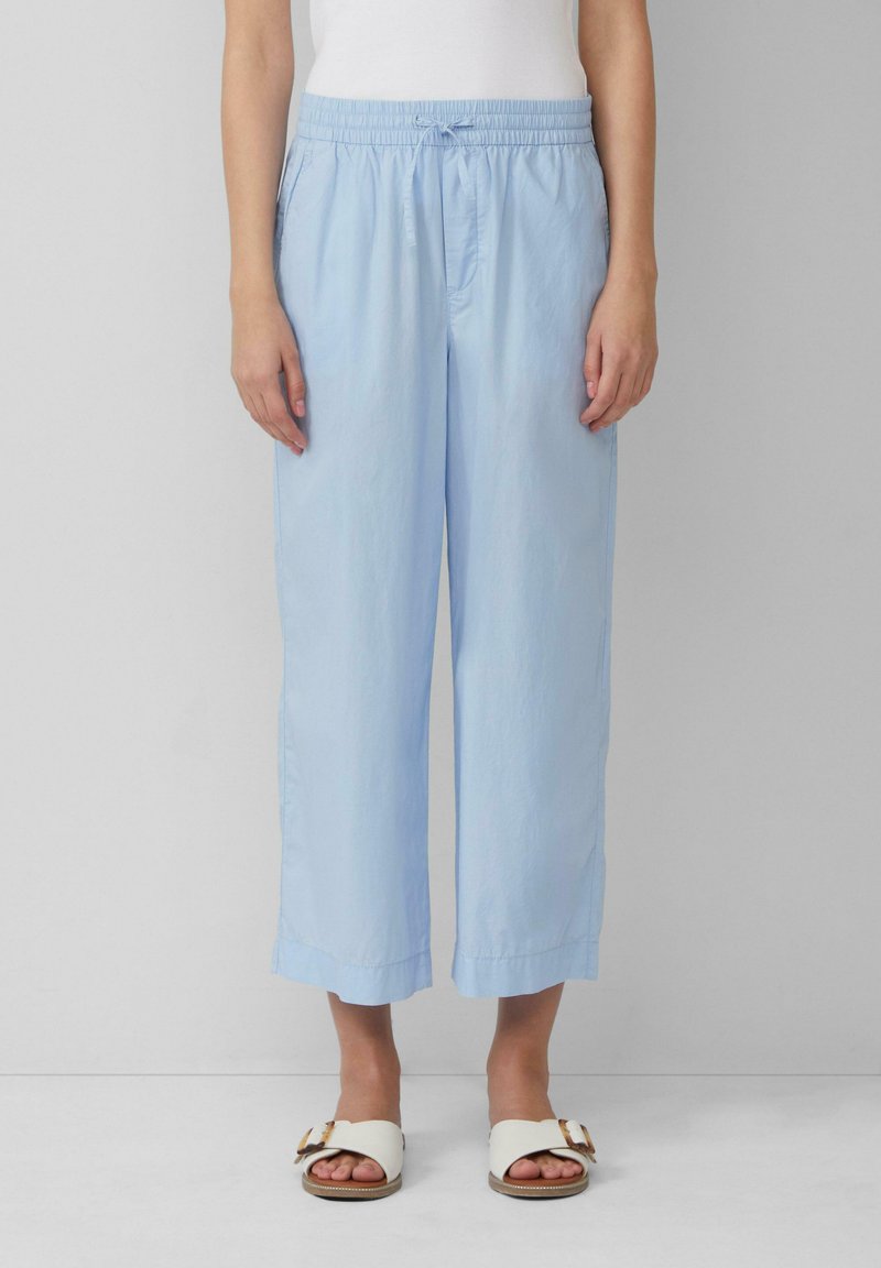 Pantalons courts, amples et bleu clair avec une taille élastique et un cordon de serrage. Texture lisse, ourlets fini et poches latérales.