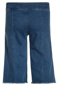 Džínové culotte kalhoty v tmavě modré barvě, s širokými nohavicemi, třepícími se lemy a dvěma vertikálními švy na zadní straně.