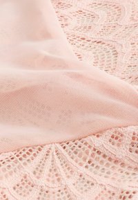 Tissu en dentelle rose pâle avec motifs floraux et superposition de mailles fines, mettant en valeur une texture délicate et des détails de design complexes.