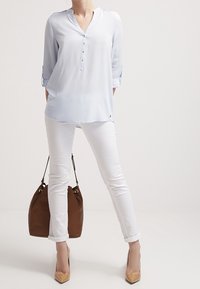 Ljusblå, långärmad, knappad skjorta; slät tyg; kombinerad med vita byxor och en brun handväska; beige högklackade skor; avslappnad passform.