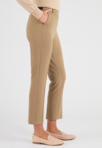 Beige op maat gemaakte broek met zijzakken, rechte pijpen, een gladde textuur en een middel hoge taille, gedragen met lichtroze instap schoenen.