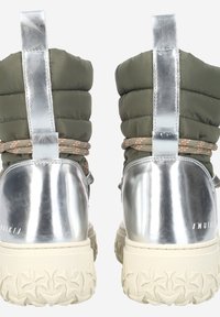 Green puffy ankle boots with metallic silver heel and reflective accents. Textured sole with lug pattern and decorative lacing detail.