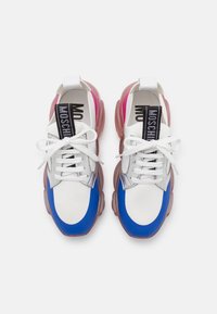 Flerfärgade sneakers med övre del i blått, vitt och silver; genomskinlig rosa sula; platta skosnören; svart "MOSCHINO"-märkning på tungan.
