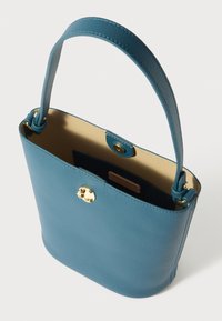 Mala de mão em pele azul com textura suave, forma arredondada e fecho em tom dourado. O interior é de uma cor bege mais clara. Possui uma única alça para ombro.