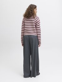 Gestreifter Pullover in Rosa und Burgunderrot, mit lockerer Passform und gerippten Bündchen. Kombiniert mit weit geschnittenen grauen Hosen aus einem strukturierten Stoff.